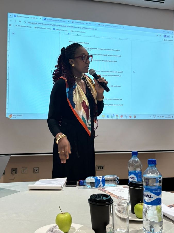 Nancy-Olive speaking to a room with a microphone