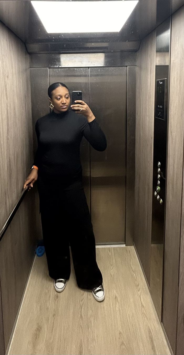 Nancy-Olive in an all-black outfit taking a mirror selfie in a lift
